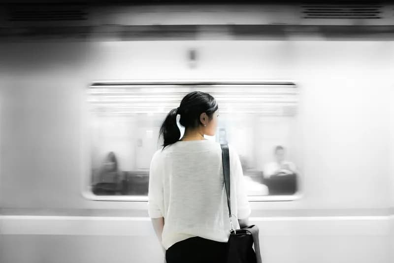 A woman standing with her back to the camera, while a train passes in front of her.