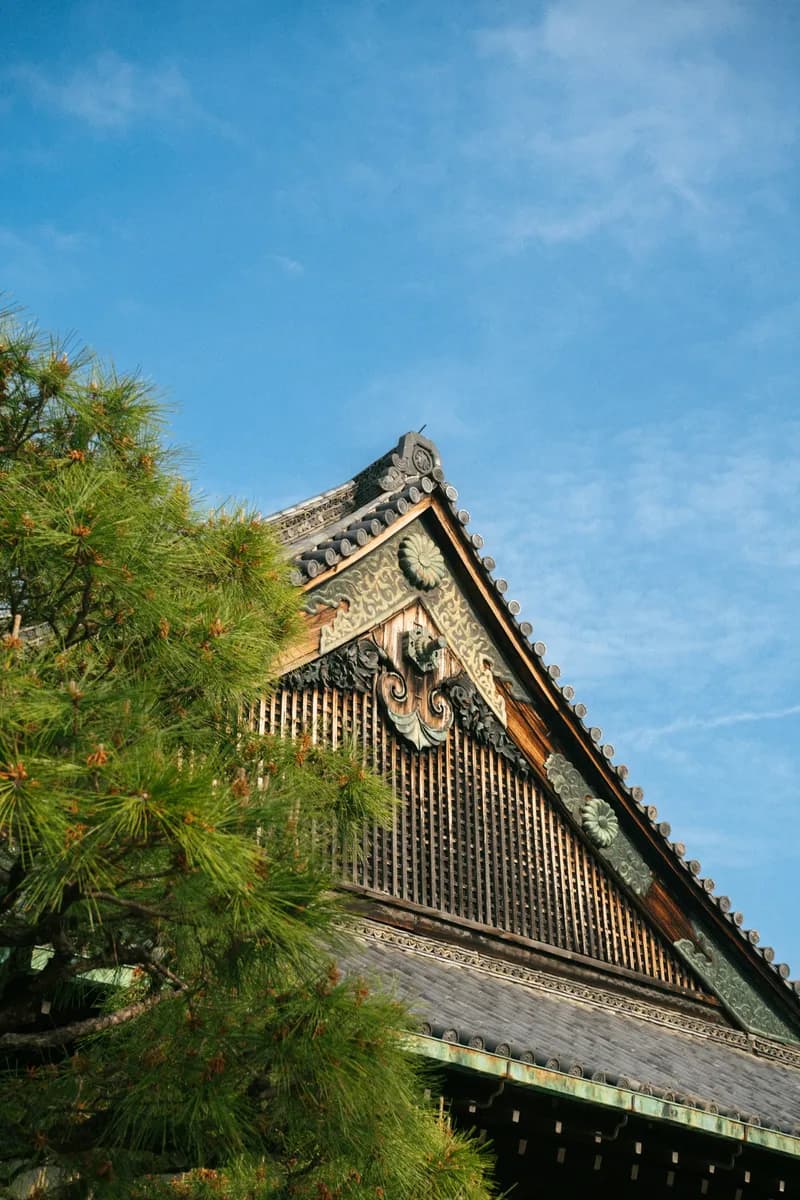 Traditional Japanese temple roof with ornate wooden architecture against blue sky