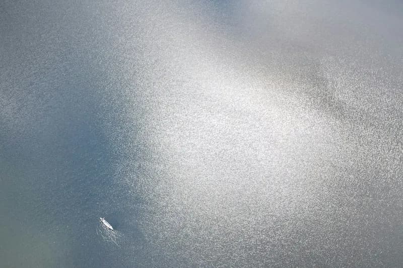 Picture from above of a tiny canoe in the middle of the vast, featureless surface of a lake.