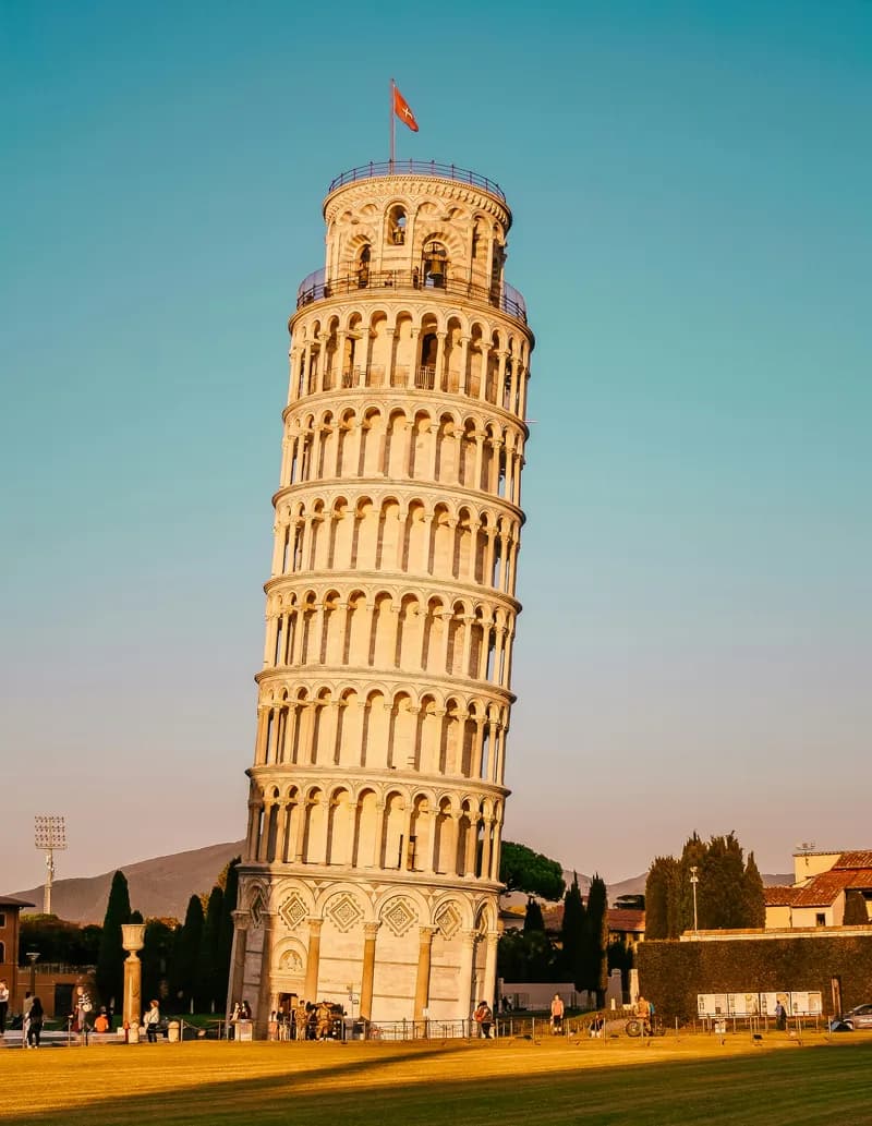 Photo of the reclining tower of Pisa. A regular and elegant tower with many rows of arches, perfectly designed if not for the problem that its base gave way on one side, leaving it inclined by several degrees.