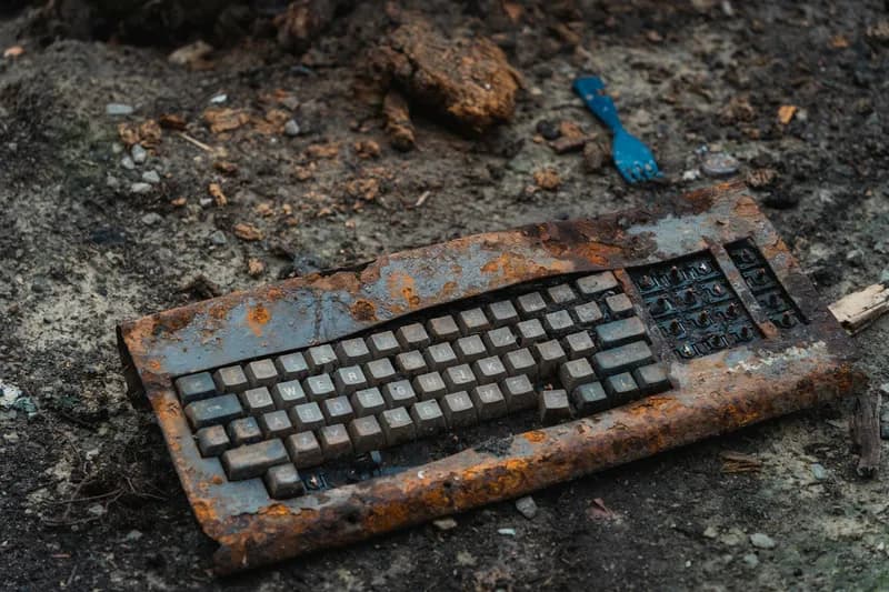 A rusty keyboard abandoned in the mud.