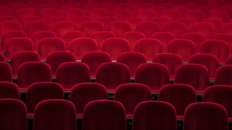 Rows of empty red velvet theater seats.