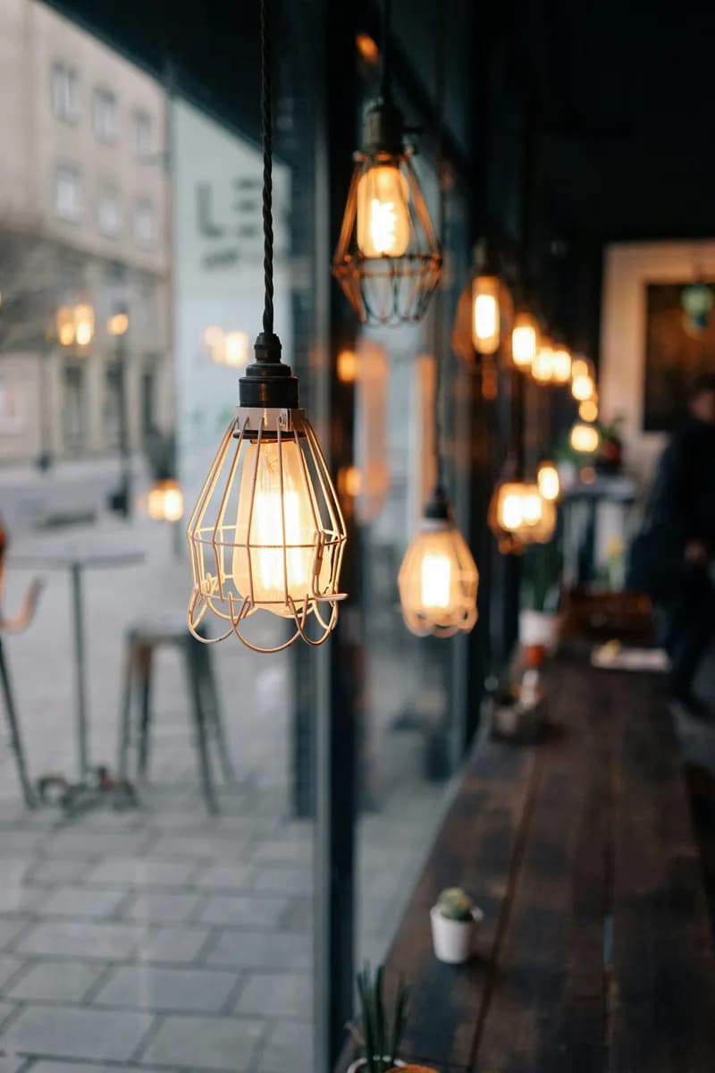 Picture of a corner of a cozy cafe, with a wooden table and warm lightbulbs in a row.