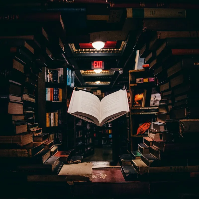 view of floating open book from stacked books in library