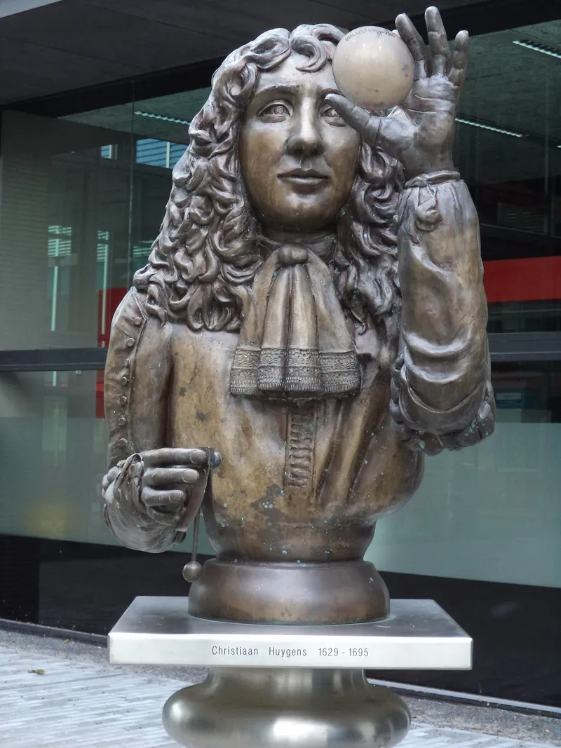 Bronze bust statue of Christian Huygens holding a circular object in front of his face.