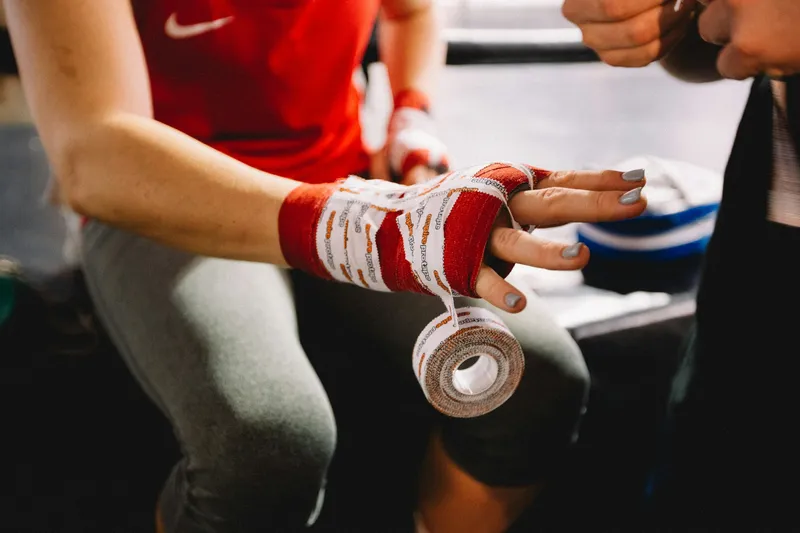 An athlete's hand being wrapped in tape by someone.