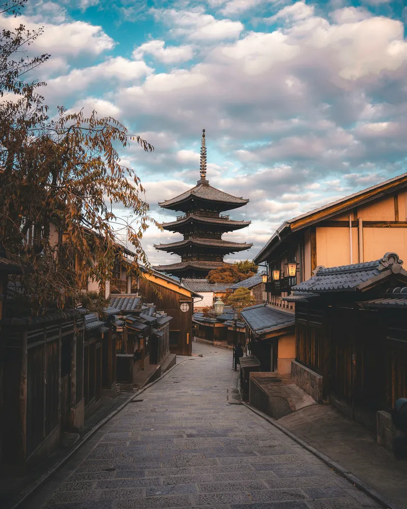 Traditional Kyoto street at dusk with wooden buildings leading to a five-story pagoda