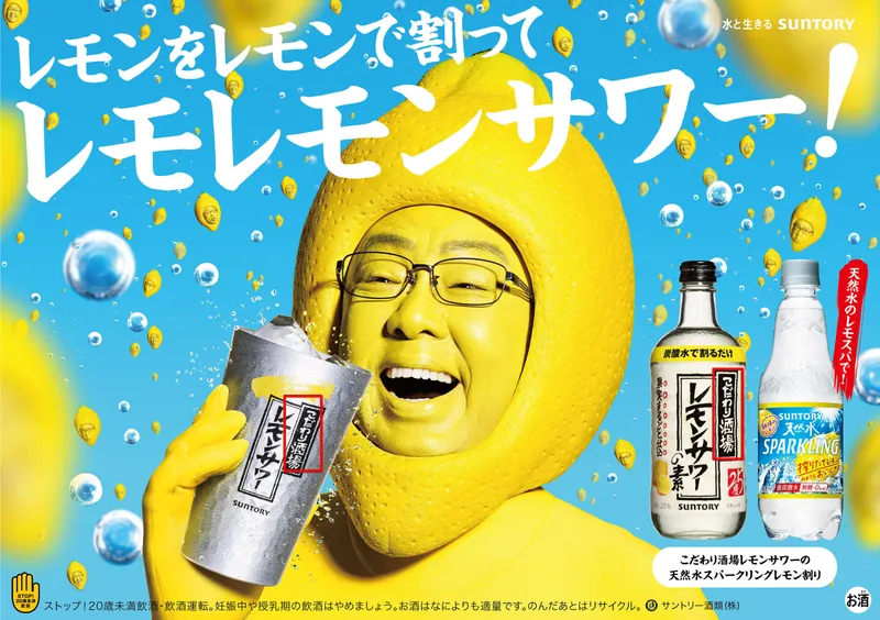 An advertisement for suntory lemon sour with a man in a lemon costume. A part of the can is highlighted, containing the word kodawari in Japanese symbols. Another lemon-flavored alcoholic drink. Here the brand itself, operated by Suntory, is called "Kodawari Sakaba" or "Kodawari Watering Hole".