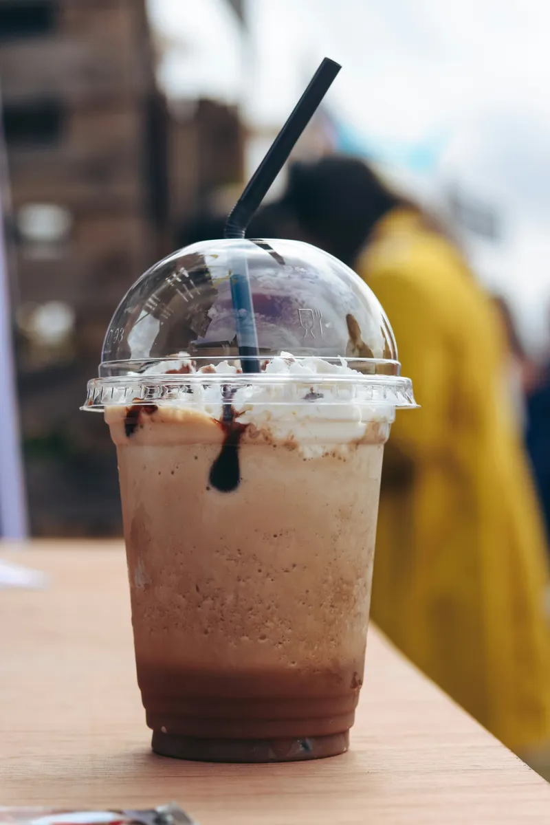 Picture of a chocolate milkshake with whipped cream in a plastic cup.